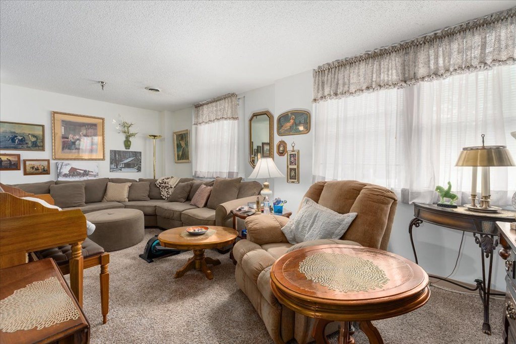 A living room with a brown couch, a wooden table, and a lamp.