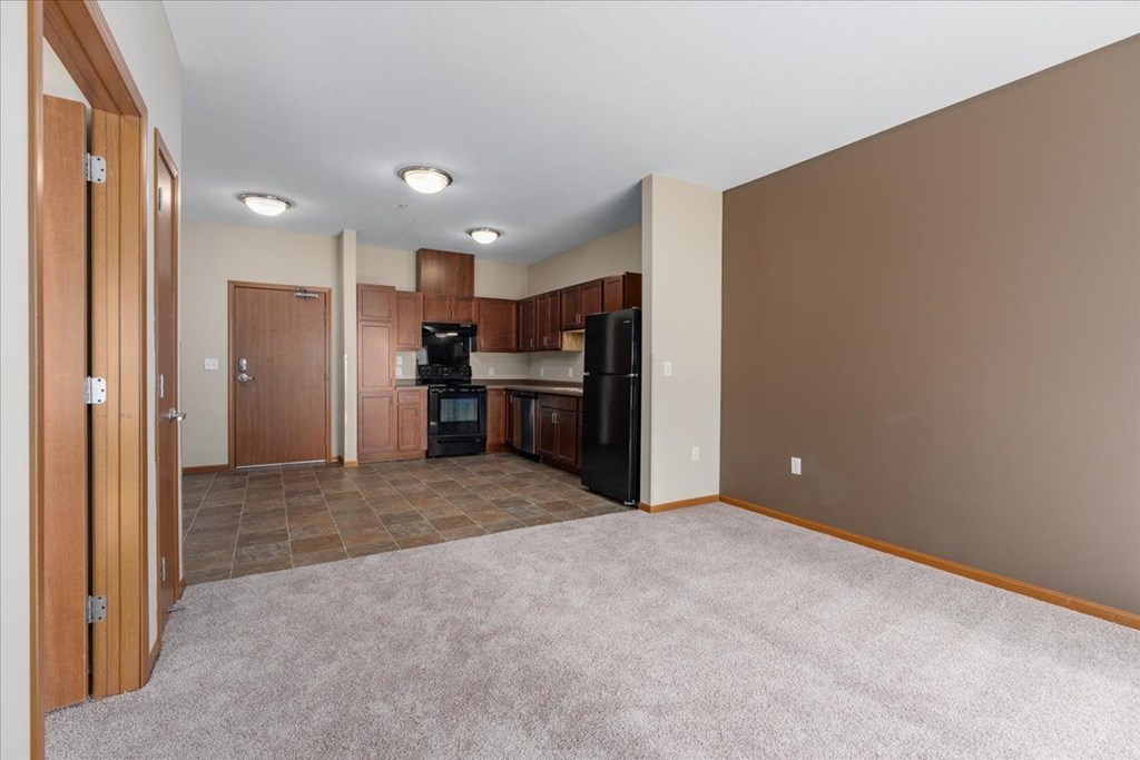 A kitchen area with brown cabinets and a black refrigerator.