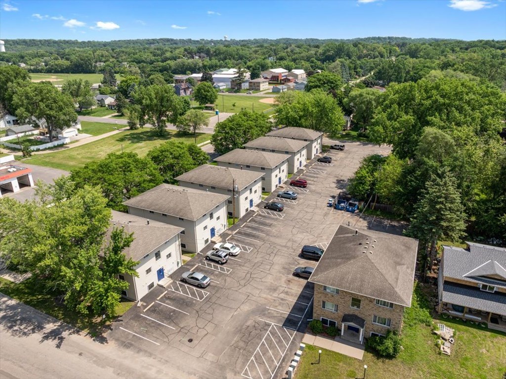 A parking lot with several cars and buildings in the background.