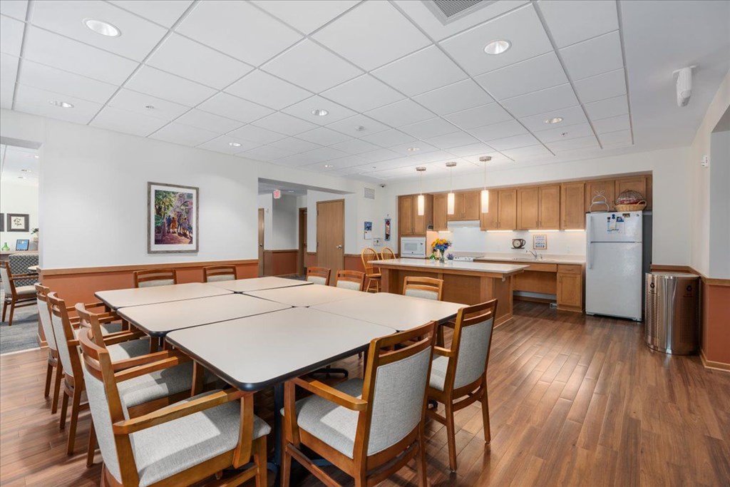 A kitchen with a table and chairs in the foreground and a refrigerator in the background.