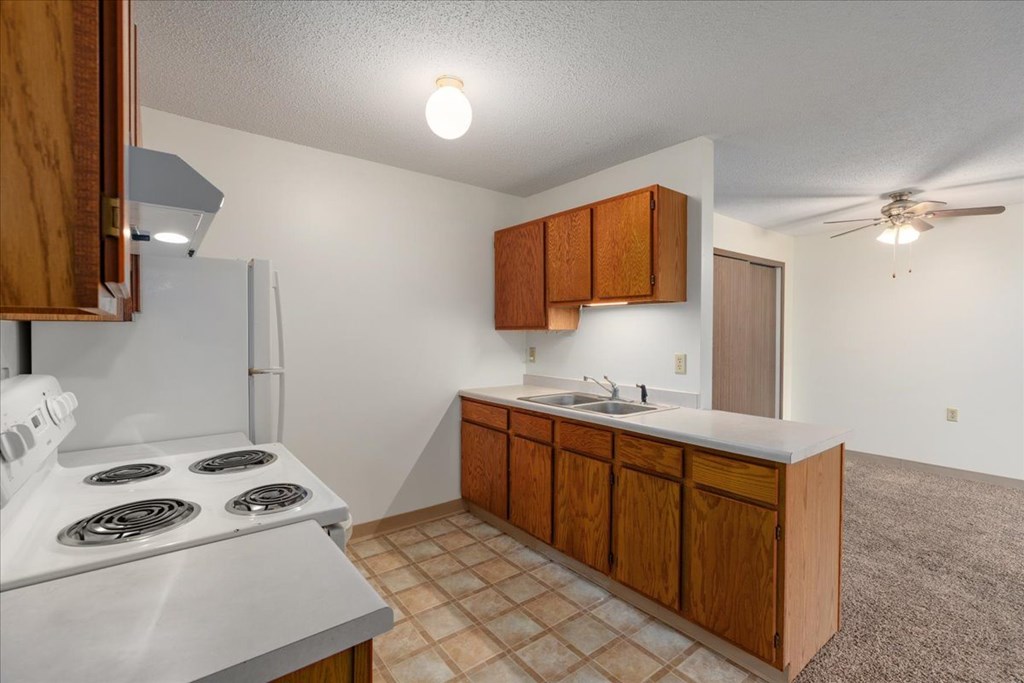 A kitchen with a white stove top oven and a white refrigerator.