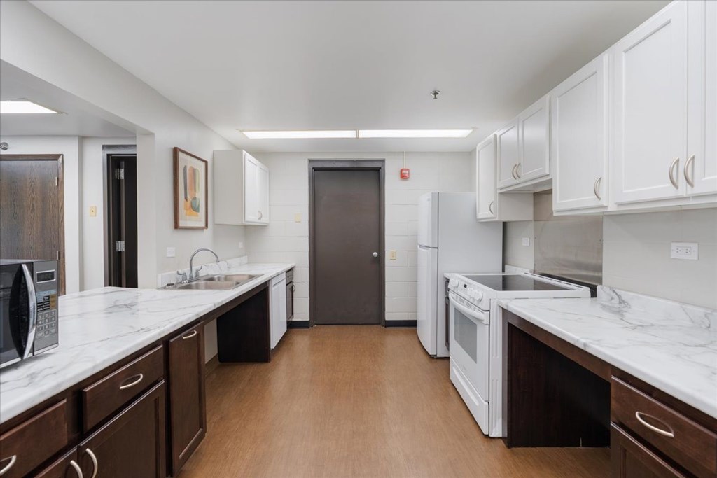 A kitchen with white cabinets and a marble countertop.