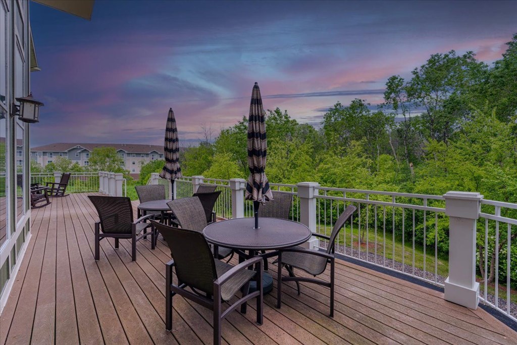 A deck with a table and chairs overlooking a forest.