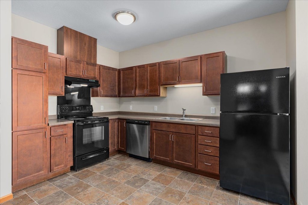 A kitchen with brown cabinets and black appliances.