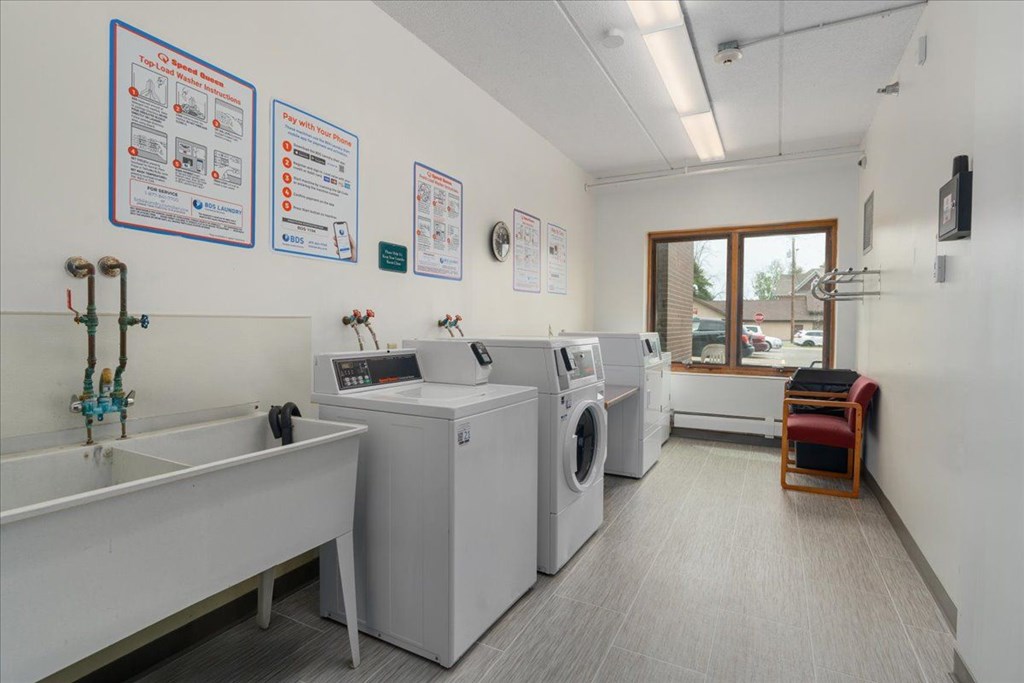 A laundry room with a washer and dryer, a sink, and a sign on the wall.