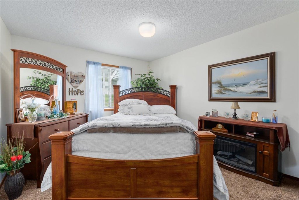 A bedroom with a bed, dresser, and a painting on the wall.