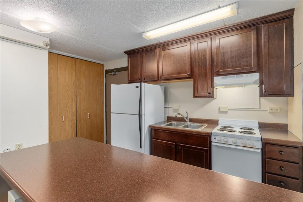 A kitchen with brown cabinets and a white refrigerator.