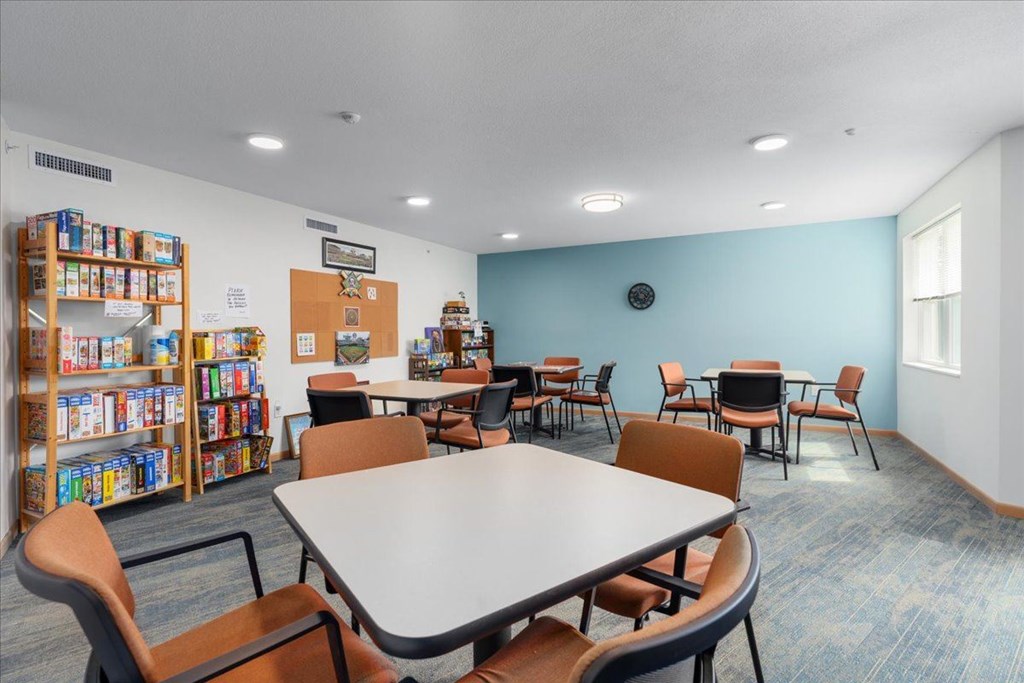 A room with a table, chairs, and a bookshelf.