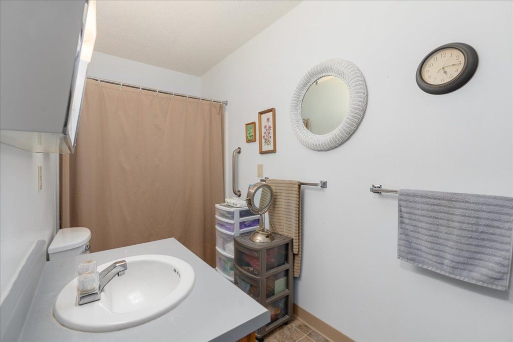 A bathroom with a white sink and a clock on the wall.