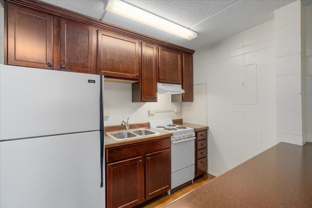 A kitchen with white appliances and brown cabinets.