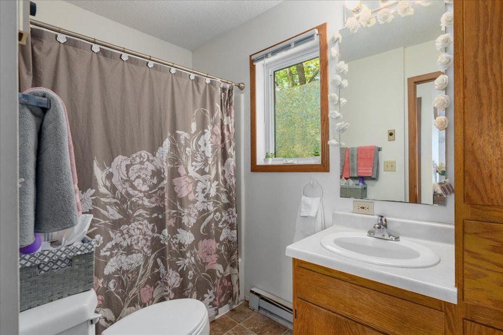 A bathroom with a floral shower curtain and a white toilet.