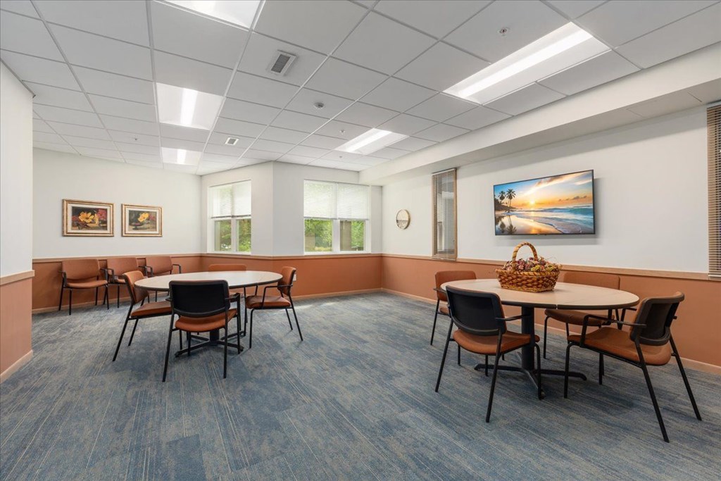A room with a table and chairs and a painting on the wall.