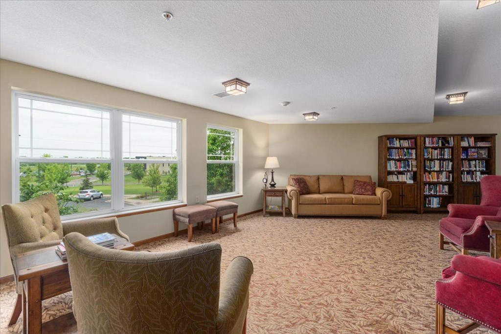 A living room with a large window, a couch, a chair, and a bookshelf.