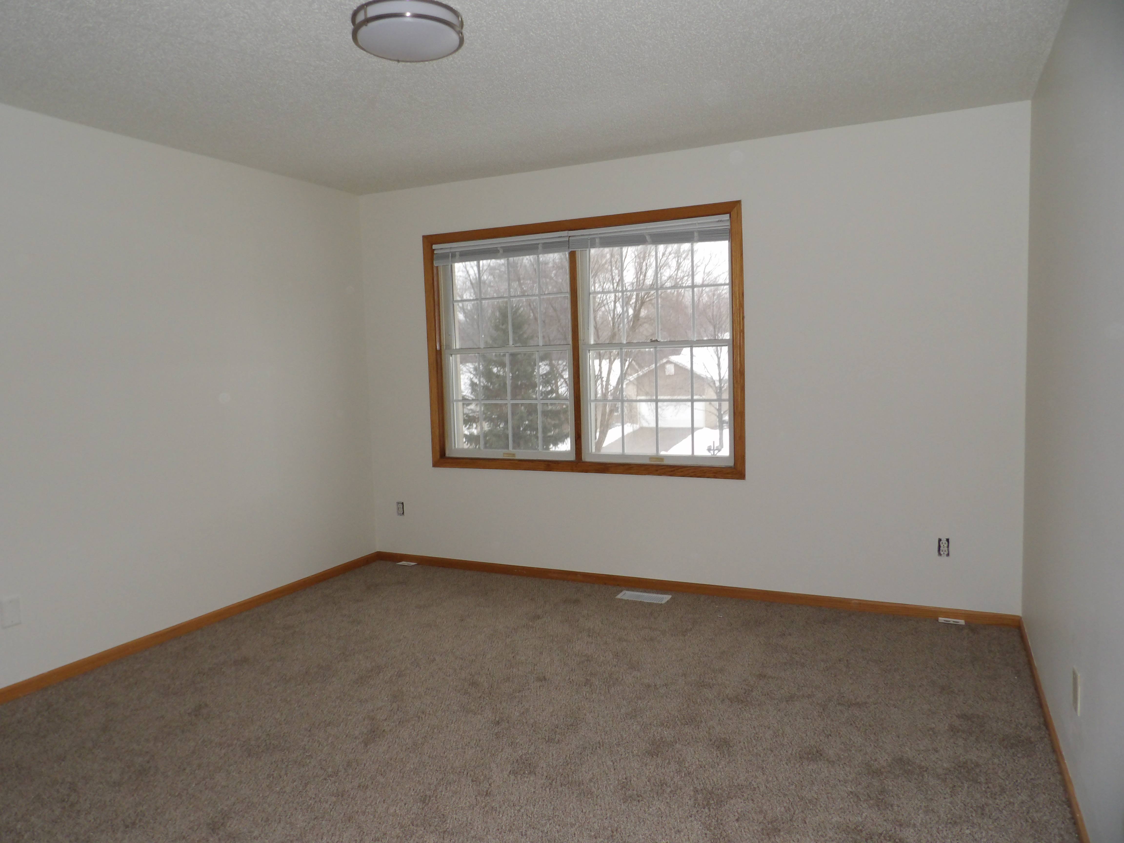 A room with a carpeted floor and a window.