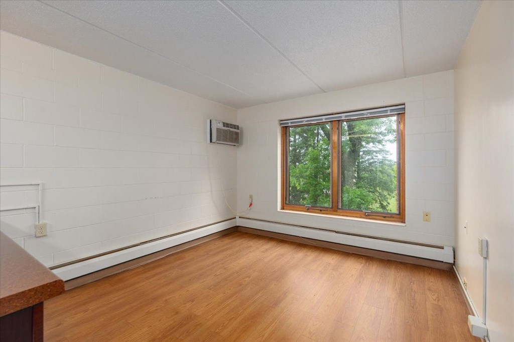 A room with a window and a wooden floor.