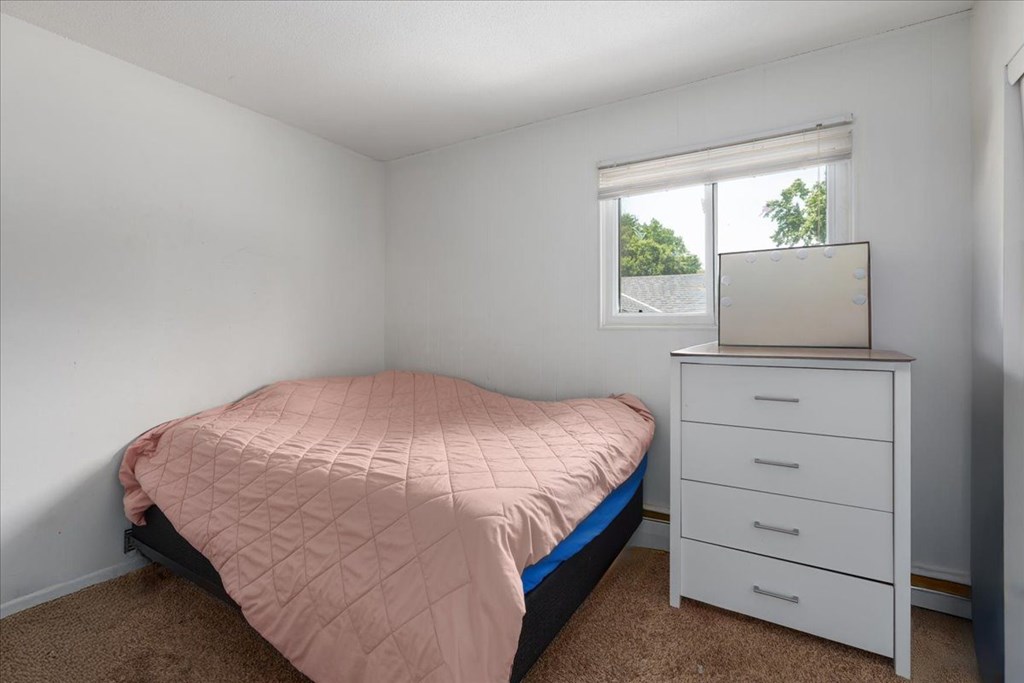 A bedroom with a bed, dresser, and window.