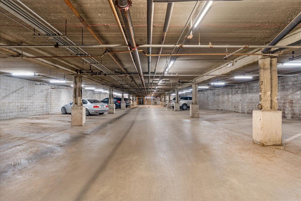 A long, empty parking garage with concrete pillars and a concrete floor.