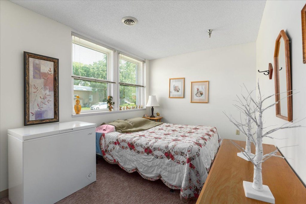 A bedroom with a bed, a window, and a picture on the wall.