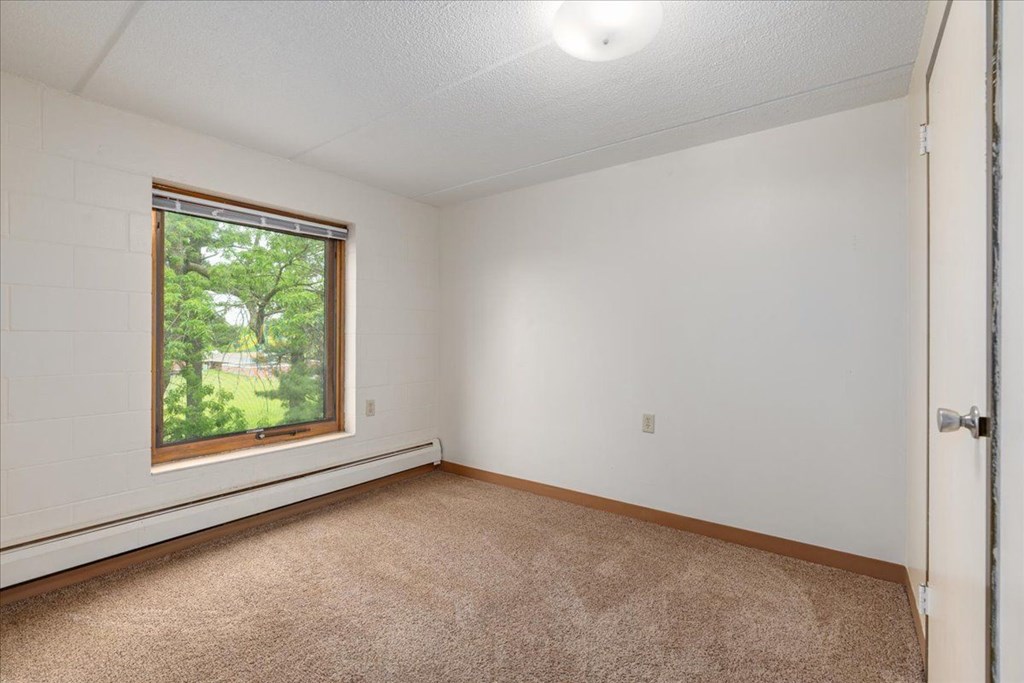 A room with a window and carpeted floor.