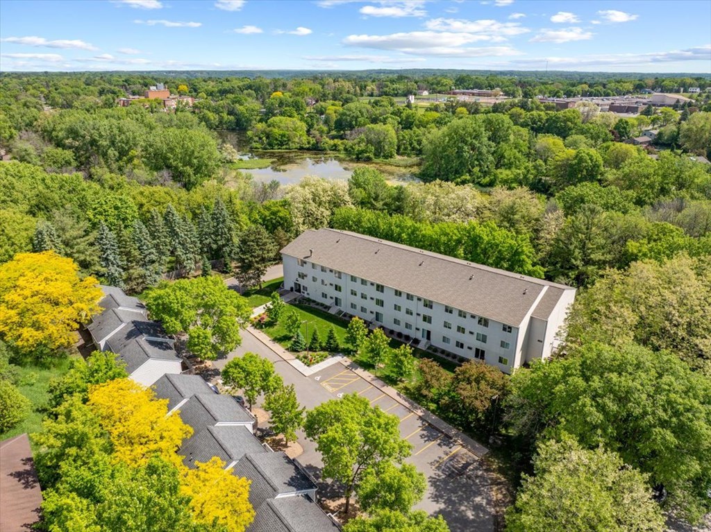 A large white building surrounded by trees and a parking lot.