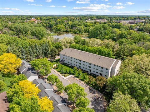 A large white building surrounded by trees and a parking lot.