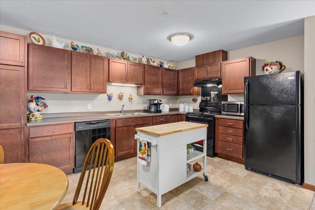 A kitchen with brown cabinets and a black refrigerator.