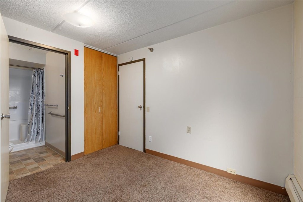 A room with a carpeted floor and two doors.
