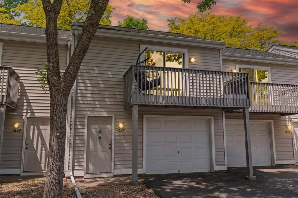 A two-story house with a balcony and garage doors.