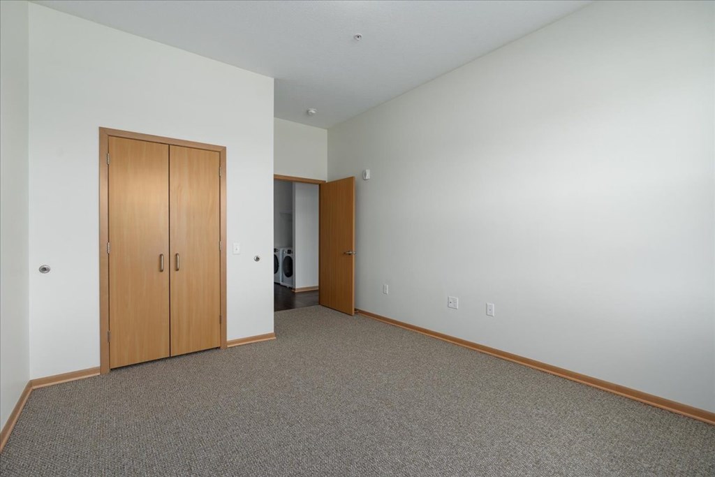 A room with a carpeted floor and two wooden doors.