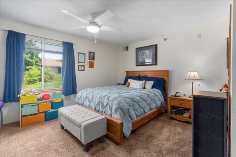 A bedroom with a bed, nightstand, and window with blue curtains.