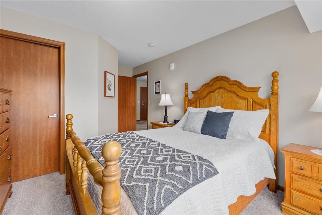 A bedroom with a large bed and a wooden dresser.