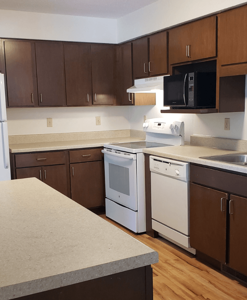 an empty kitchen with white appliances and wooden cabinets