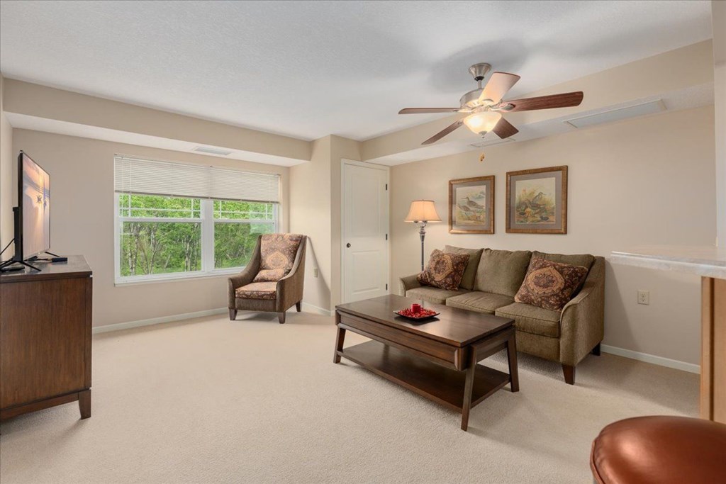 A living room with a brown couch, a brown chair, and a brown coffee table.