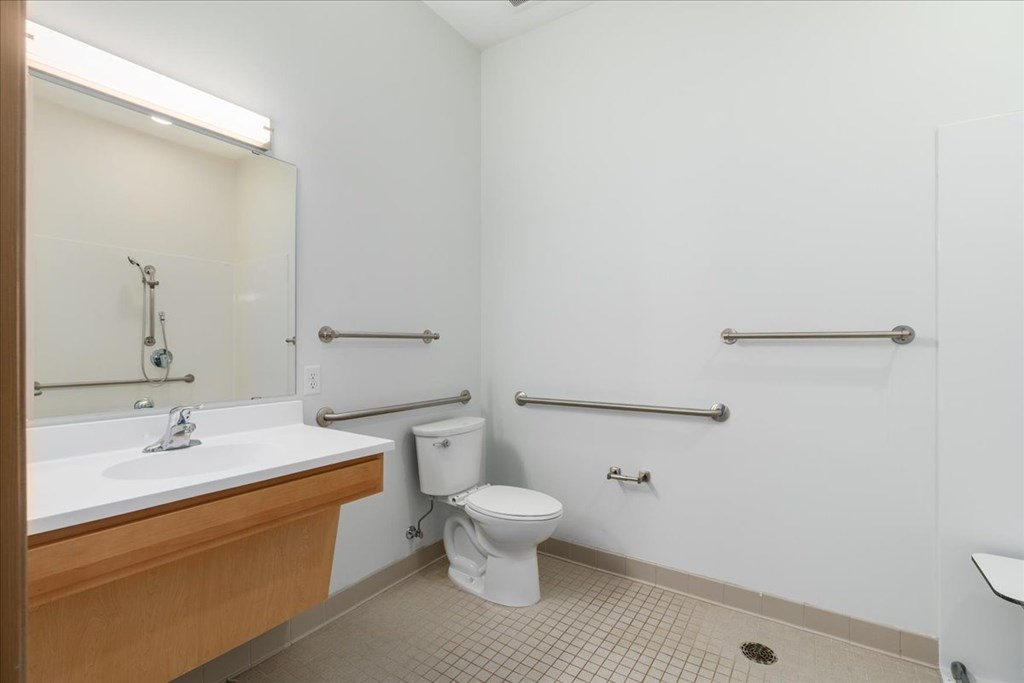 A white toilet sits in a bathroom next to a sink.