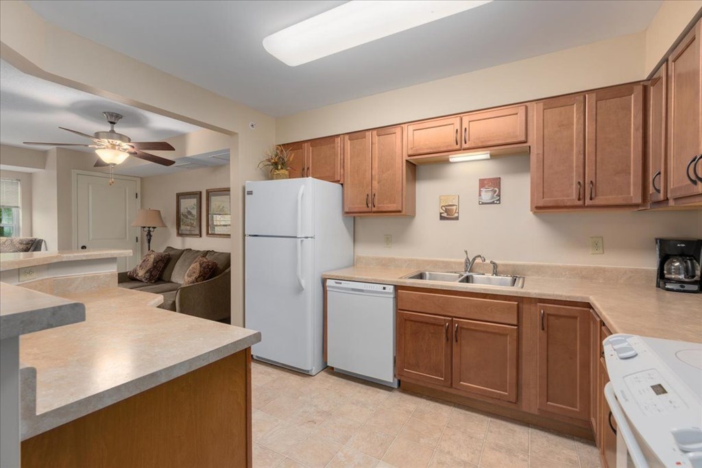 A kitchen with a white refrigerator and brown cabinets.