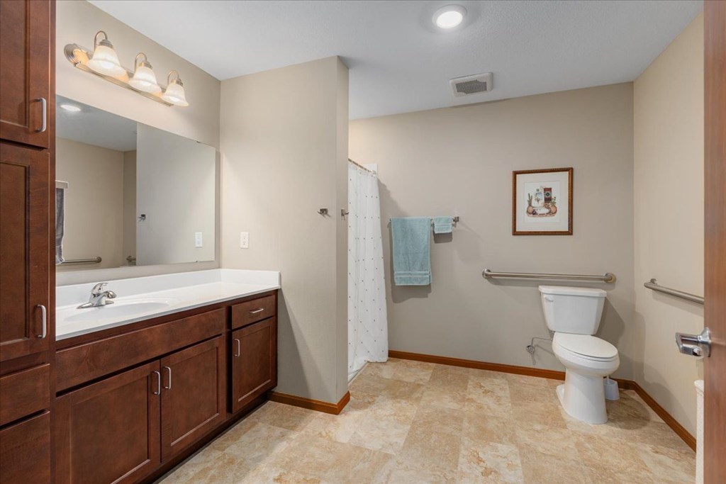 A bathroom with a toilet, sink, and a mirror.