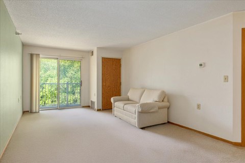 A living room with a white couch and a sliding glass door.