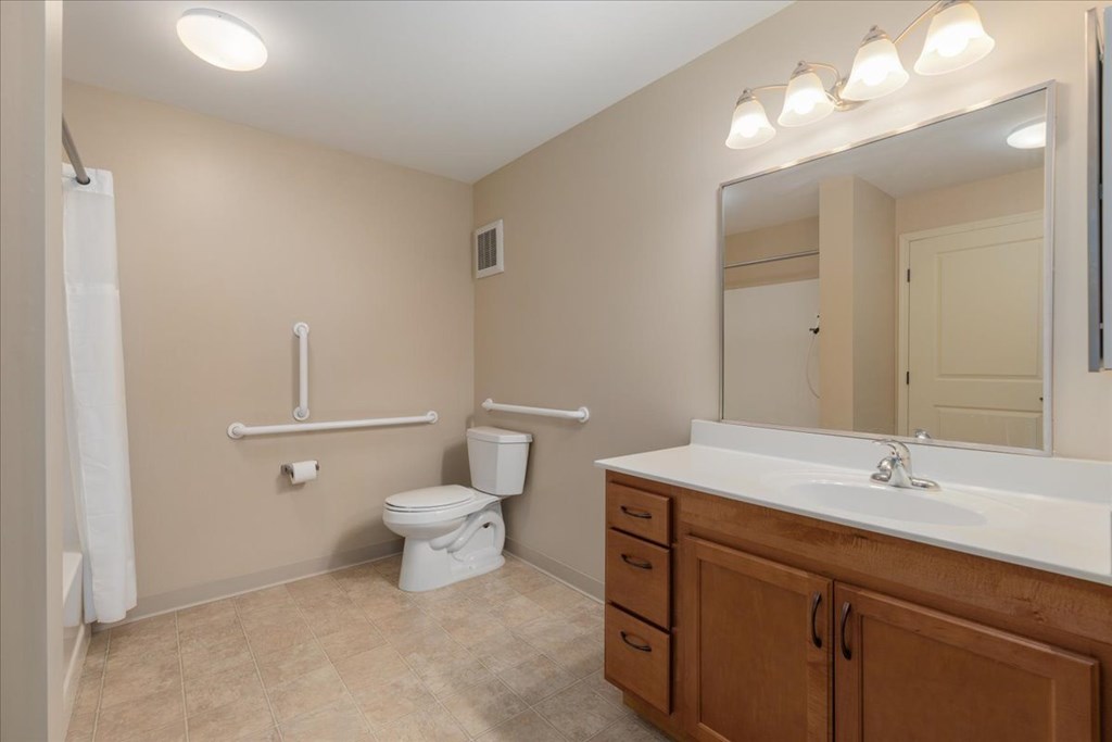 A bathroom with a toilet, sink, and mirror.