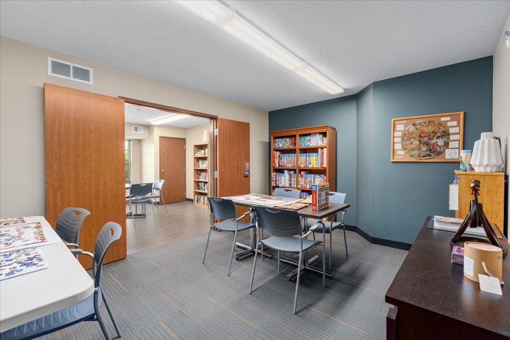 A room with a table, chairs, and a bookshelf.