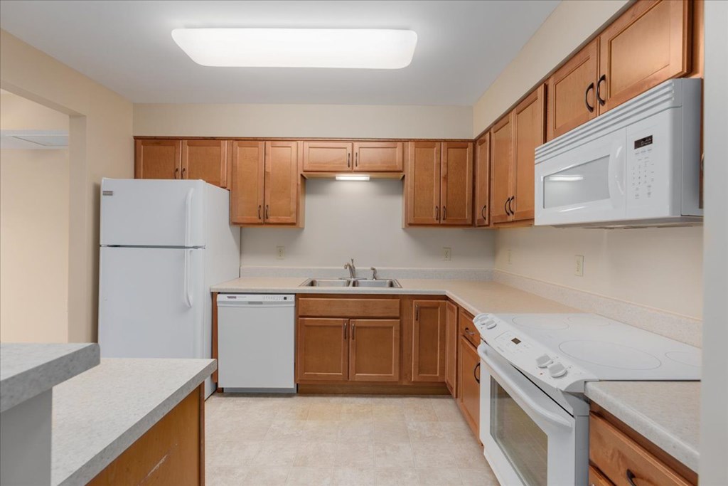 A kitchen with white appliances and wooden cabinets.