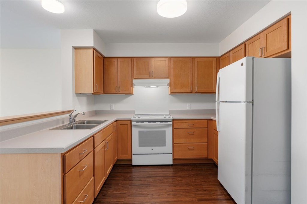 A kitchen with wooden cabinets and white appliances.