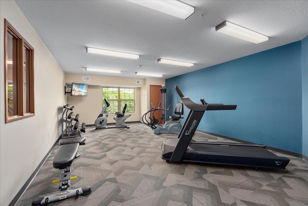 A spacious gym with a variety of equipment including treadmills, exercise bikes, and weights.