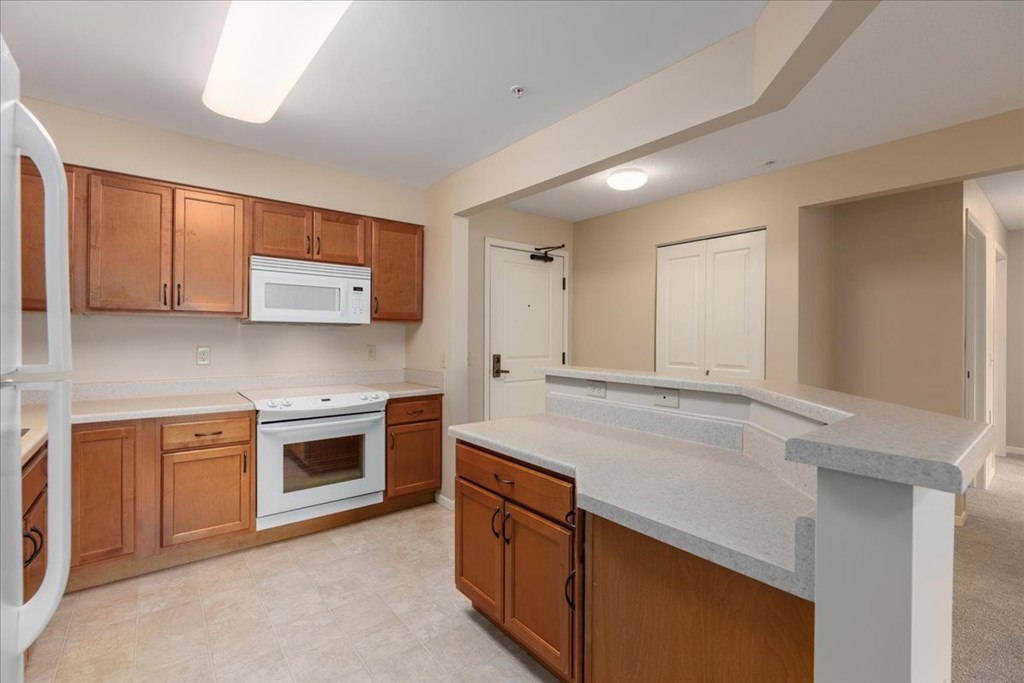 A kitchen with wooden cabinets and a white fridge.