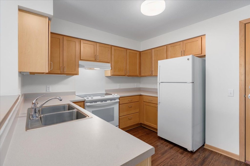 A kitchen with a white refrigerator and wooden cabinets.