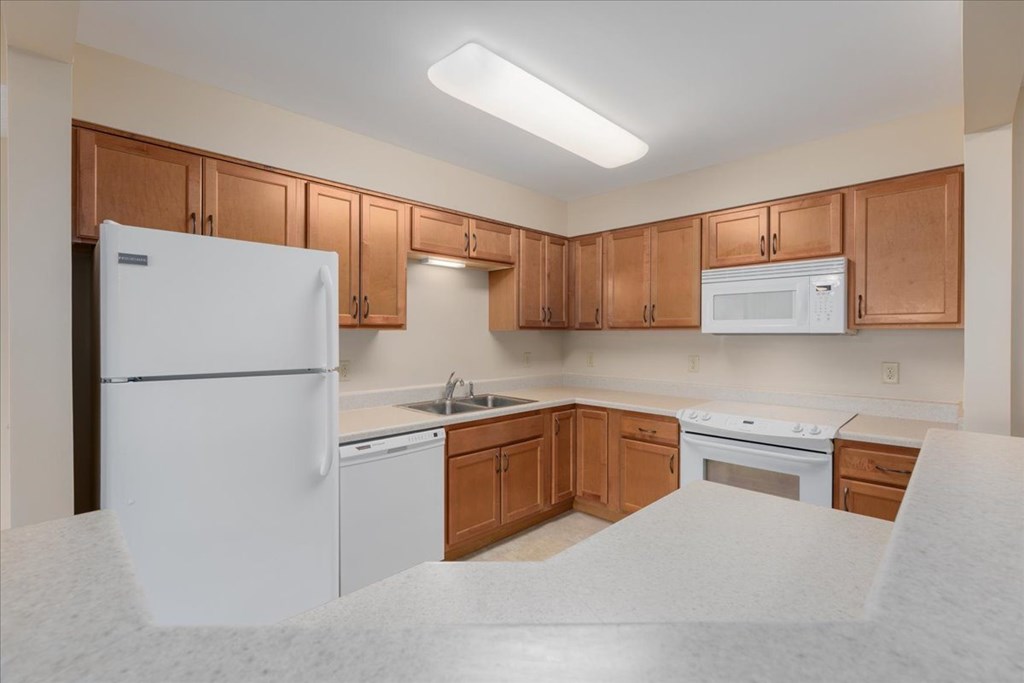 A kitchen with white appliances and wooden cabinets.