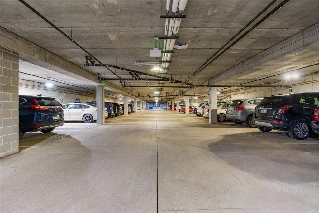 A parking garage with cars parked on both sides of the aisle.