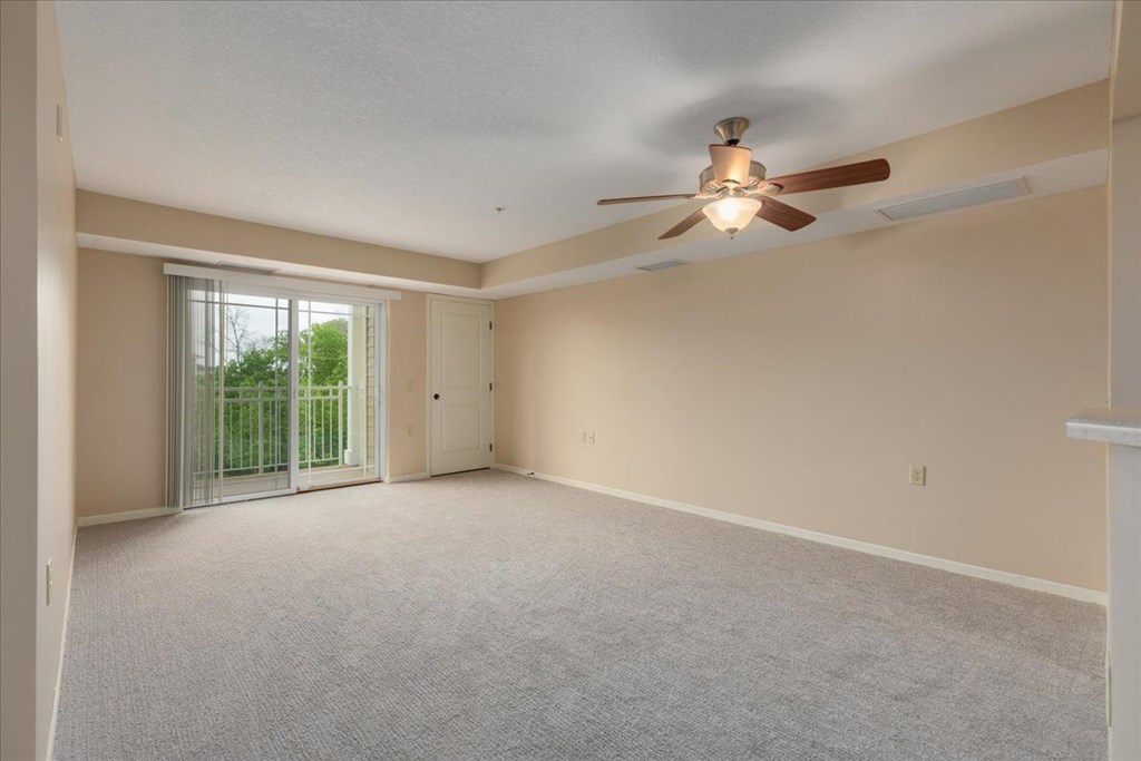 A room with a ceiling fan and carpeted floor.
