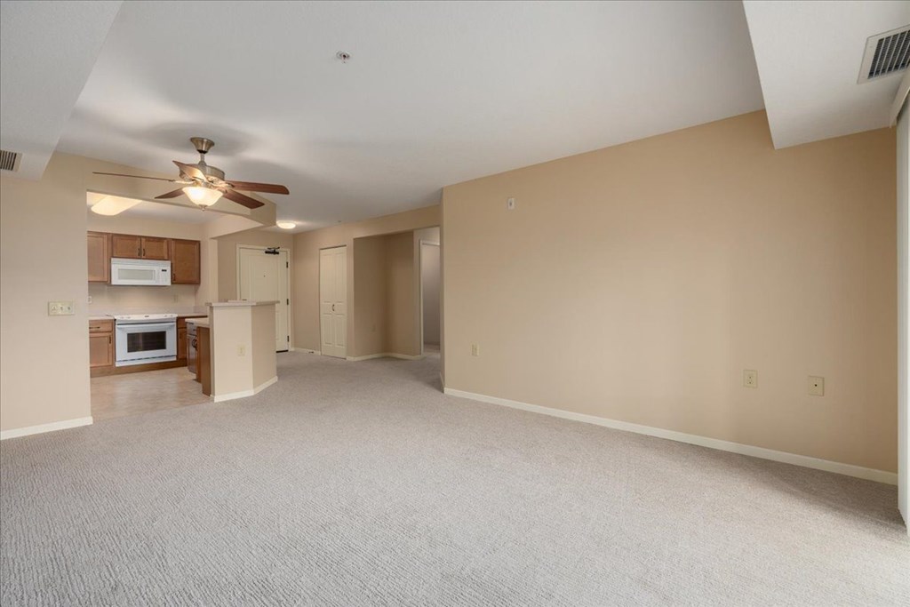 A spacious room with a ceiling fan and carpeted floor.