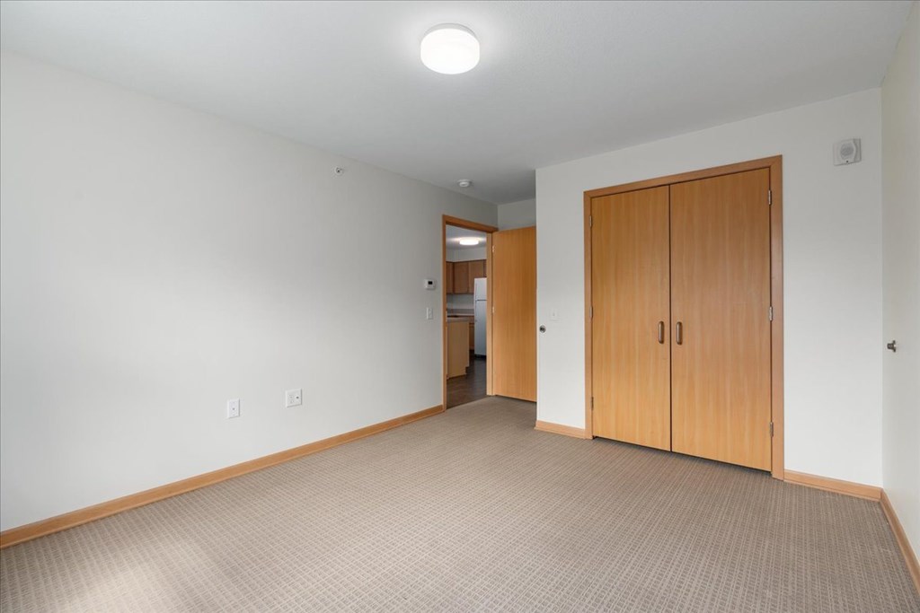 A room with a carpeted floor and a wooden door.