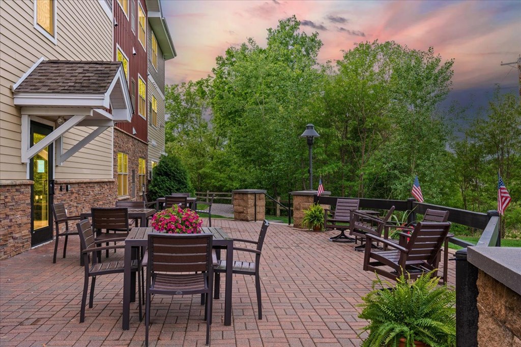 A patio with a table and chairs is surrounded by trees.